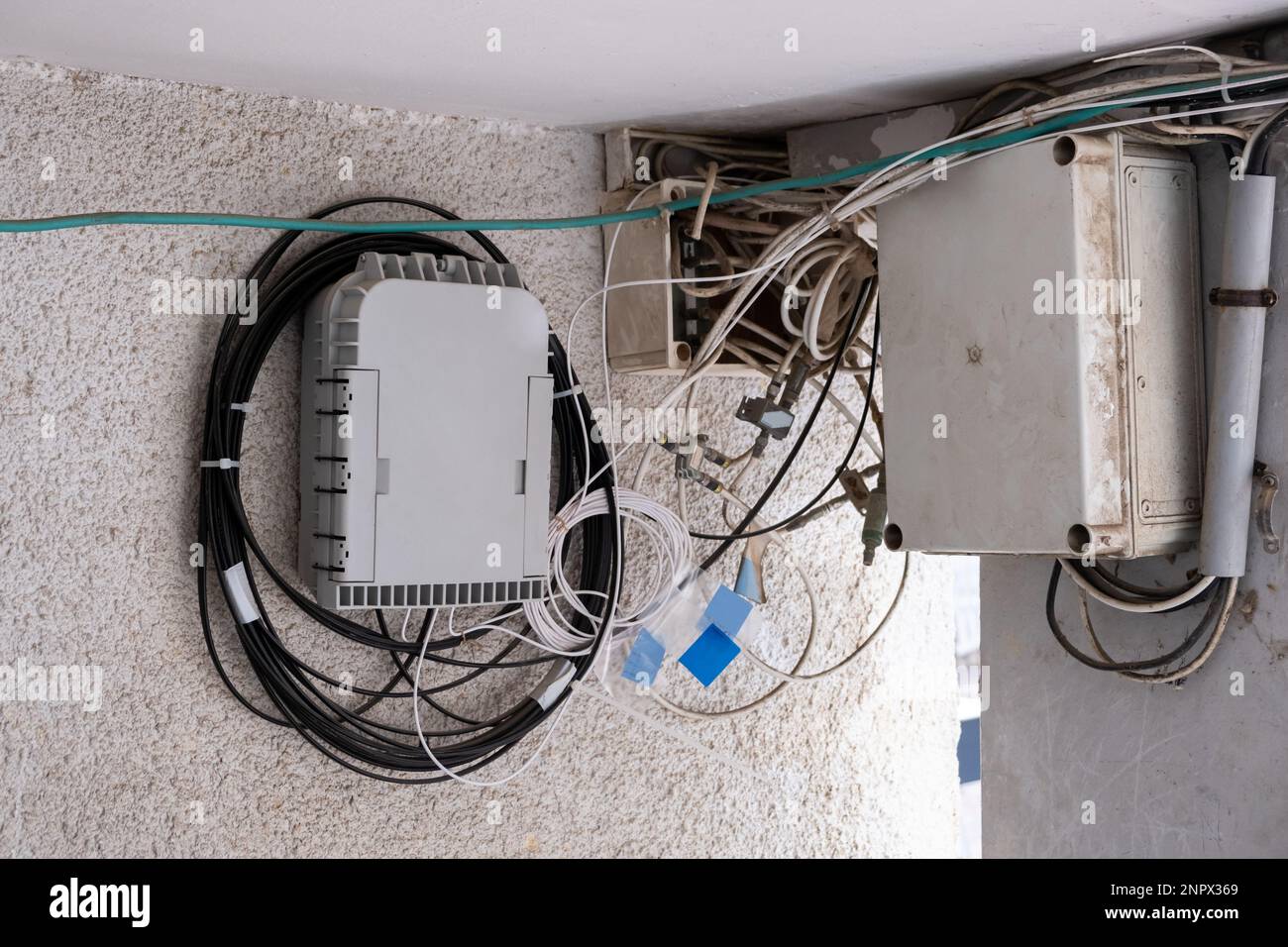 Fiber optical Network hub on wall and old tv cables in plastic box