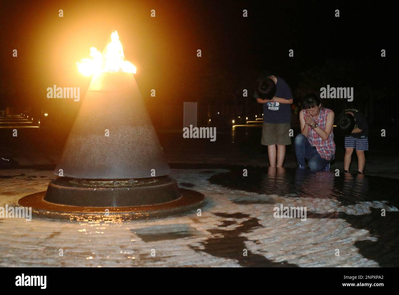 Local residents pray for the victims of the Battle of Okinawa in front of the Peace Light at the Okinawa Peace Memorial Park in Itoman City, Okinawa Prefecture June 22, 2020, on the eve of the 75th anniversary of the battle . Okinawa will mark the end of the bloodiest battle during the World War II, which claimed the lives of more than 200,000 local Okinawan as well as Japanese and American military soldiers.( The Yomiuri Shimbun via AP Images ) Stock Photo
