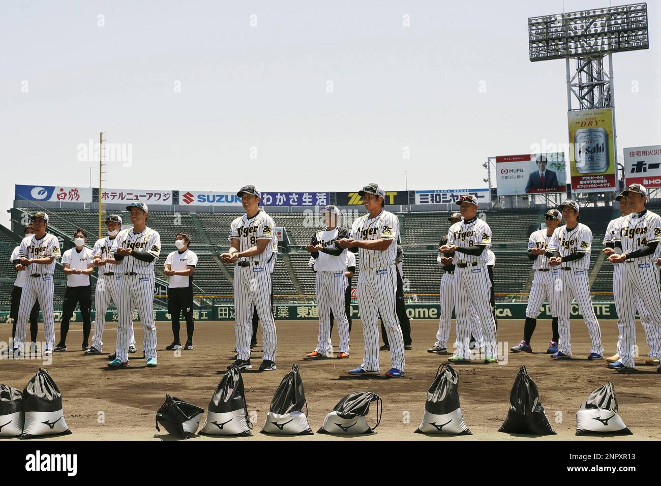 Manager Akihiro Yano, center left, and players of the Japanese professional baseball team Hanshin Tigers show dirt they collected from the grounds of Koshien Stadium in Nishinomiya, western Japan, Tuesday, June 16,