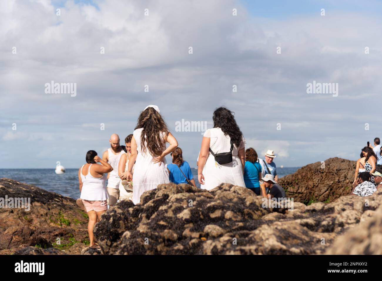 Salvador, Bahia, Brazil - February 02, 2023: People are seen on top of the rocks at Rio Vermelho beach, offering gifts to Yemanja, in Salvador, Bahia. Stock Photo