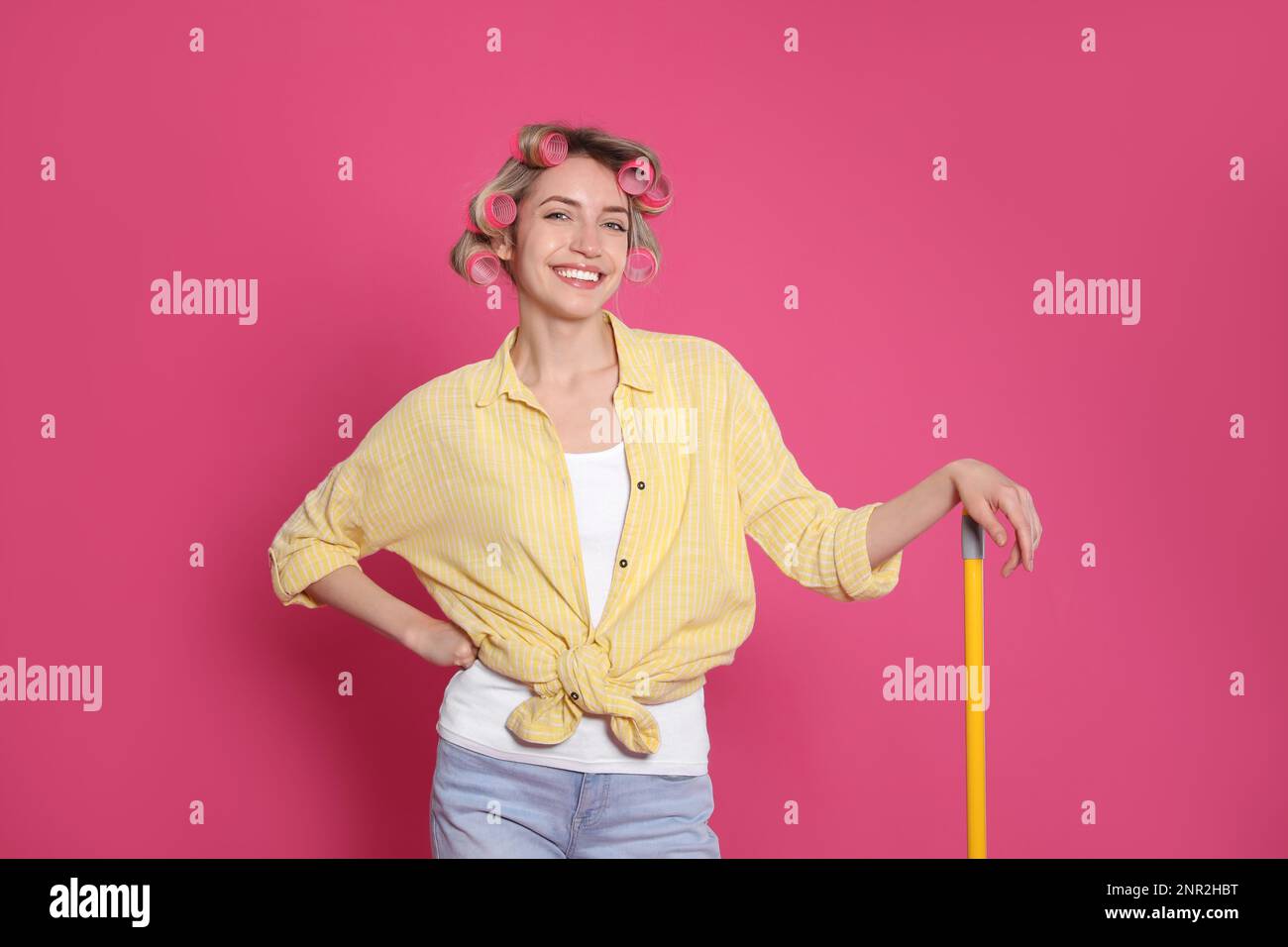 Young housewife with broom on pink background Stock Photo