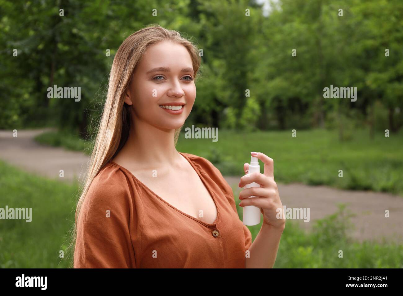Woman using insect repellent in park. Tick bites prevention Stock Photo
