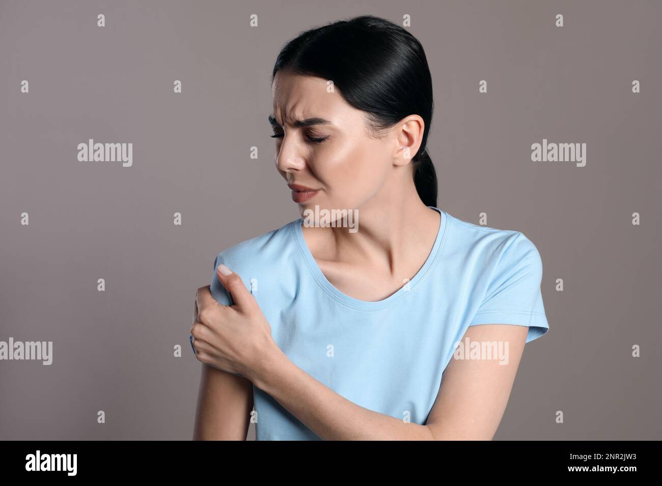 Woman suffering from shoulder pain on beige background Stock Photo