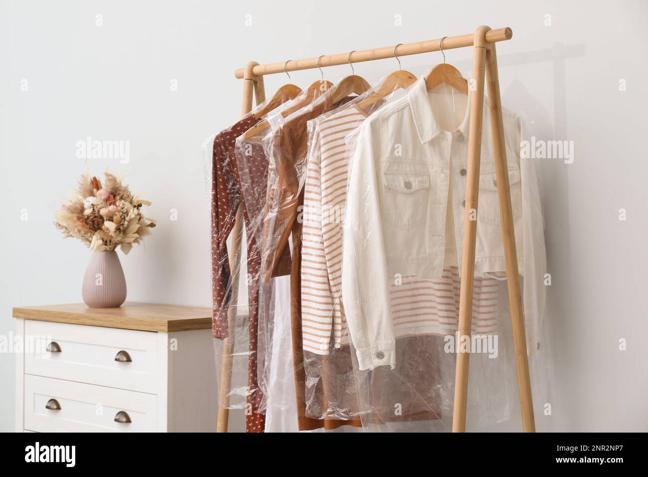 Rack with clothes in plastic bags indoors Stock Photo Alamy