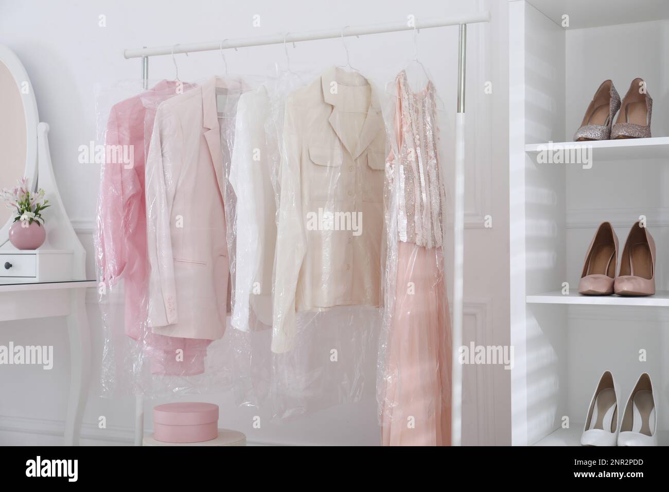 Rack with clothes in plastic bags indoors Stock Photo Alamy