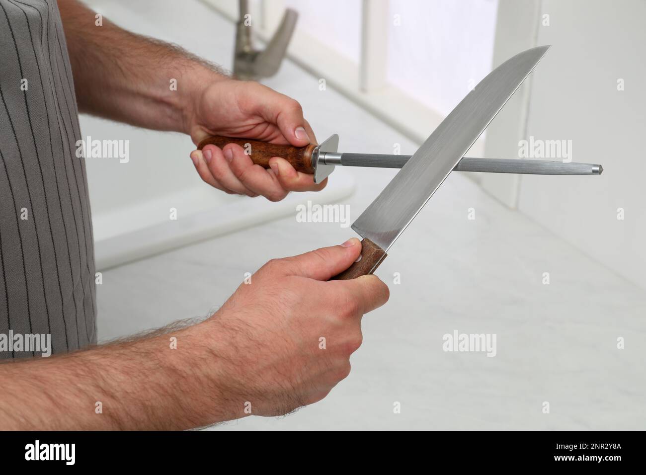 Man sharpening knife in kitchen, closeup view Stock Photo Alamy