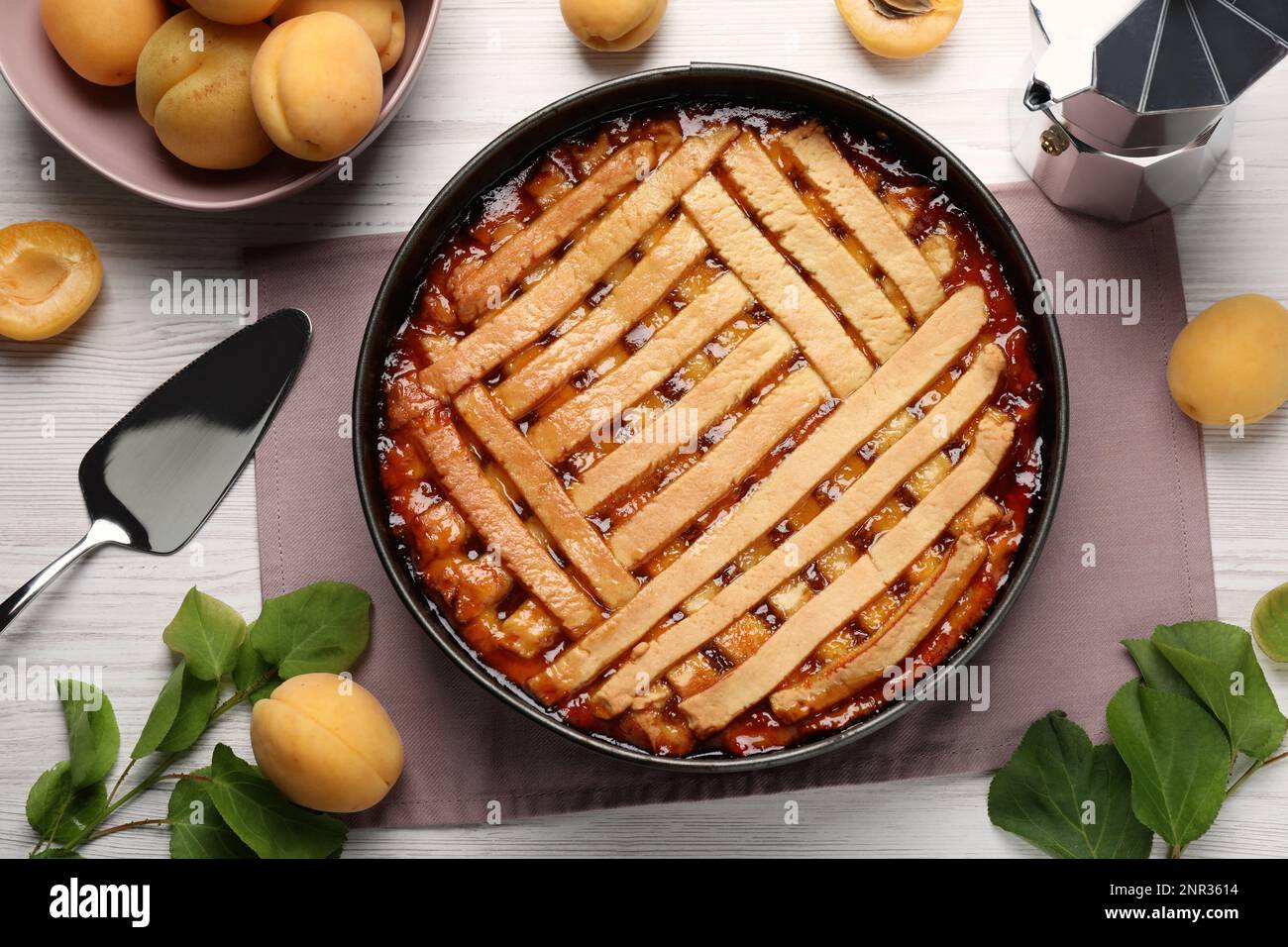 Delicious apricot pie in baking dish and fresh fruits on white wooden table, flat lay Stock Photo