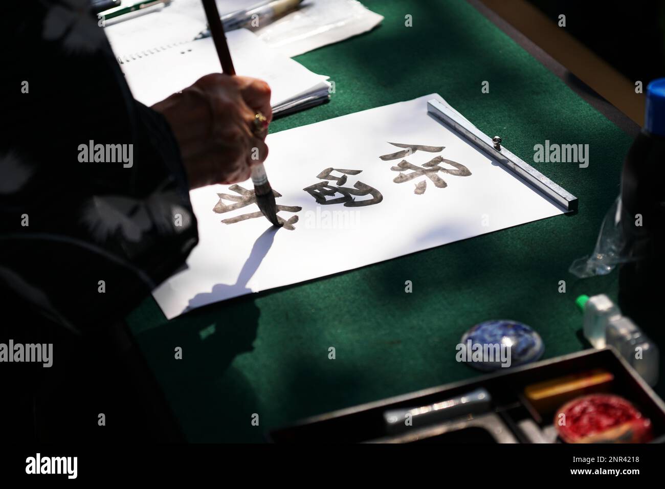 japanese calligraphy, unrecognizable person writing kanji characters with ink brush on paper, english translation: reserved Stock Photo