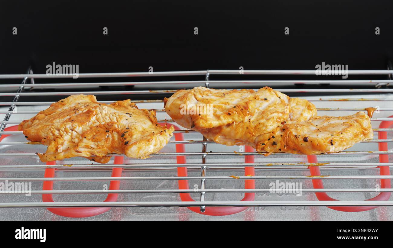 preparing marinated grilled chicken on electric table grill Stock Photo