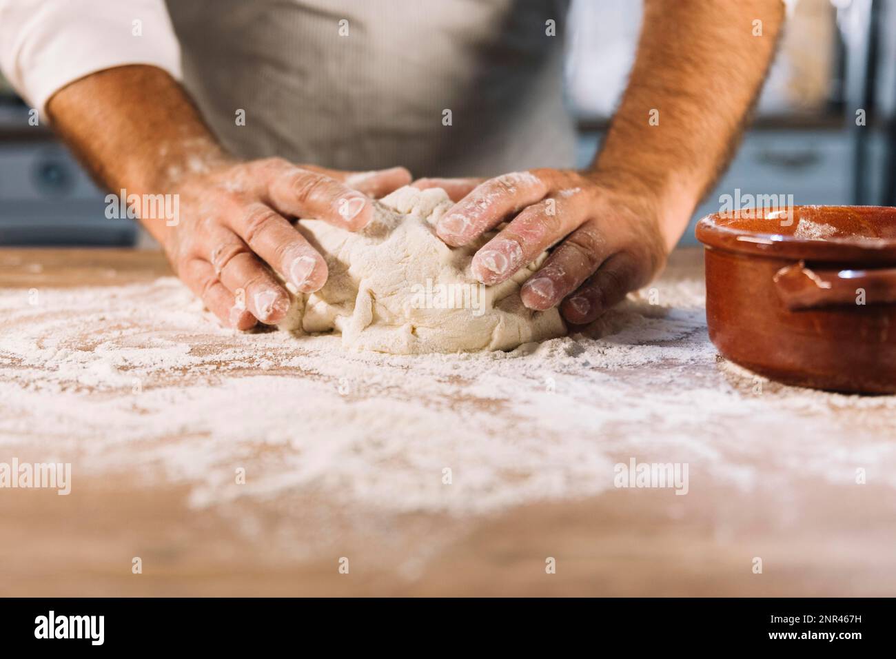 male baker kneading dough flour wooden table. Beautiful photo Stock