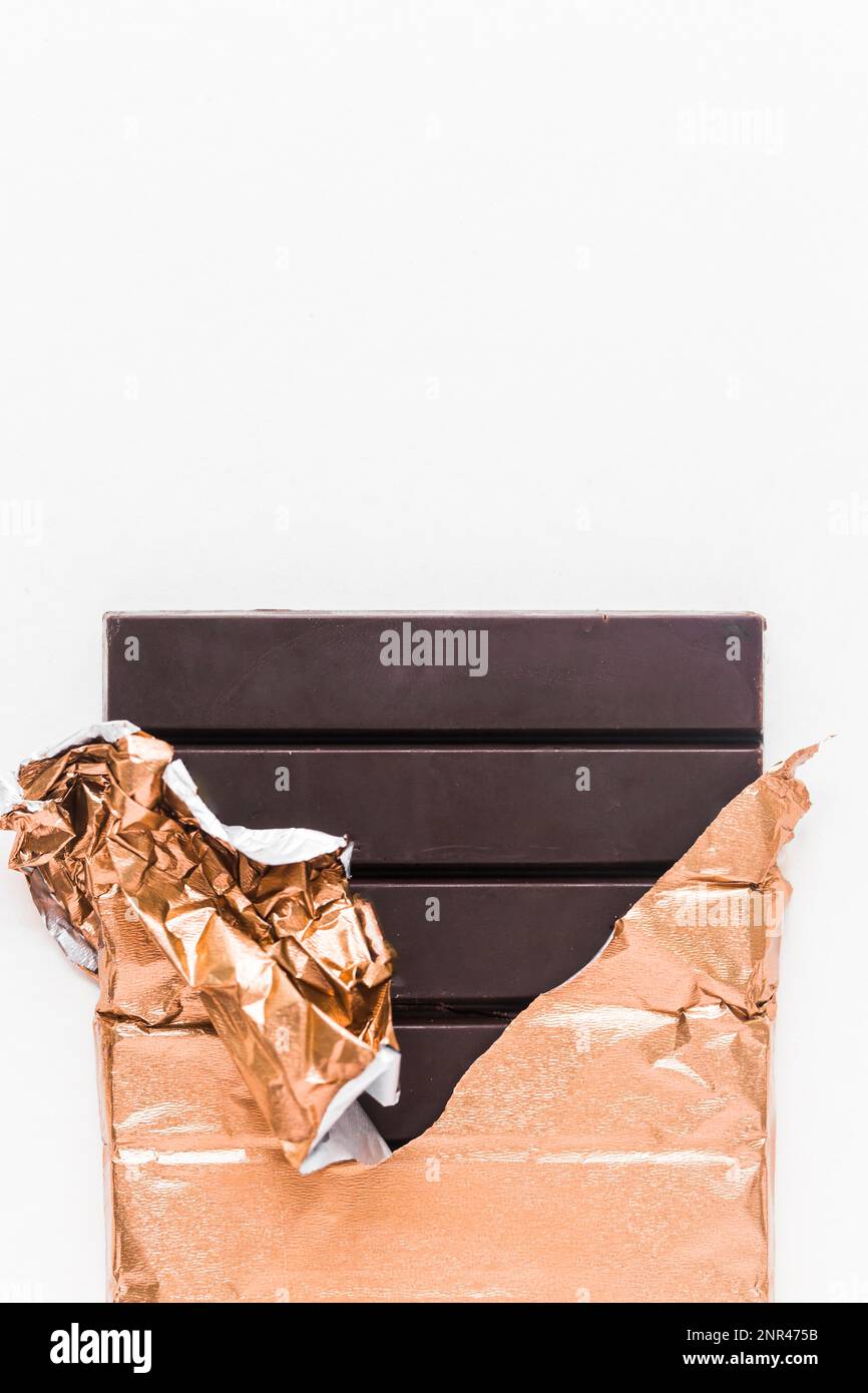 delicious chocolate bar wrapped golden foil white background Stock