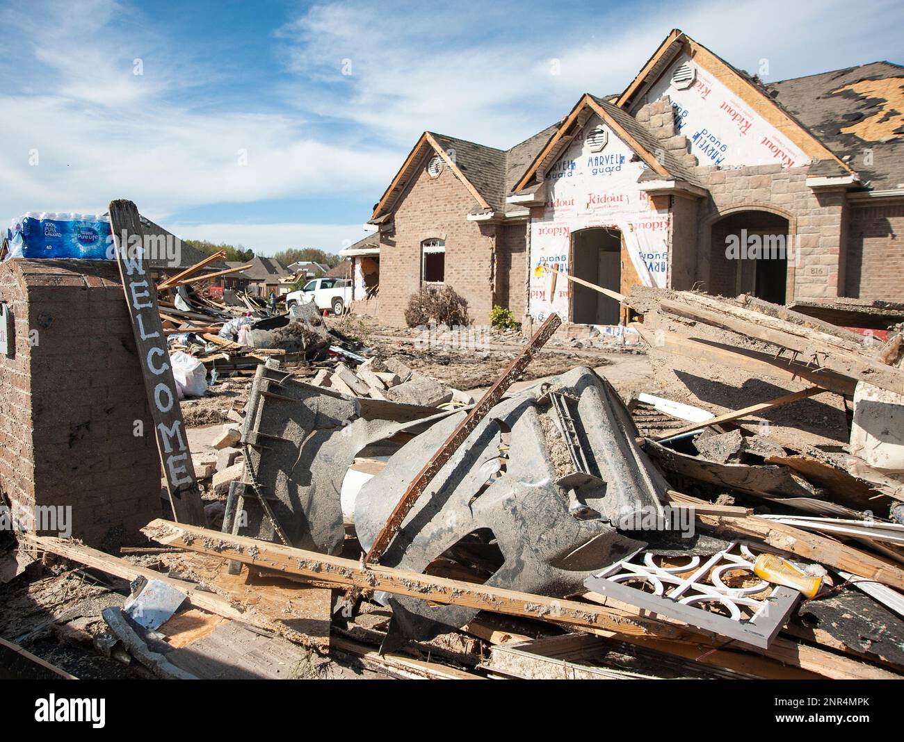 A sign leans against a mailbox amongst piles of tornado debris