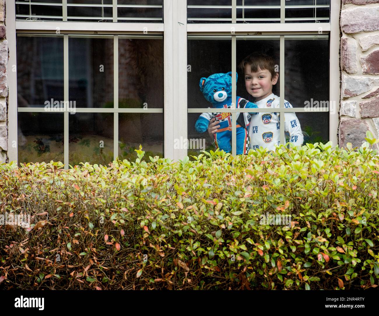 Reece Renick, 6, stands in the window with his teddy bear in the The Woods neighborhood of Tyler