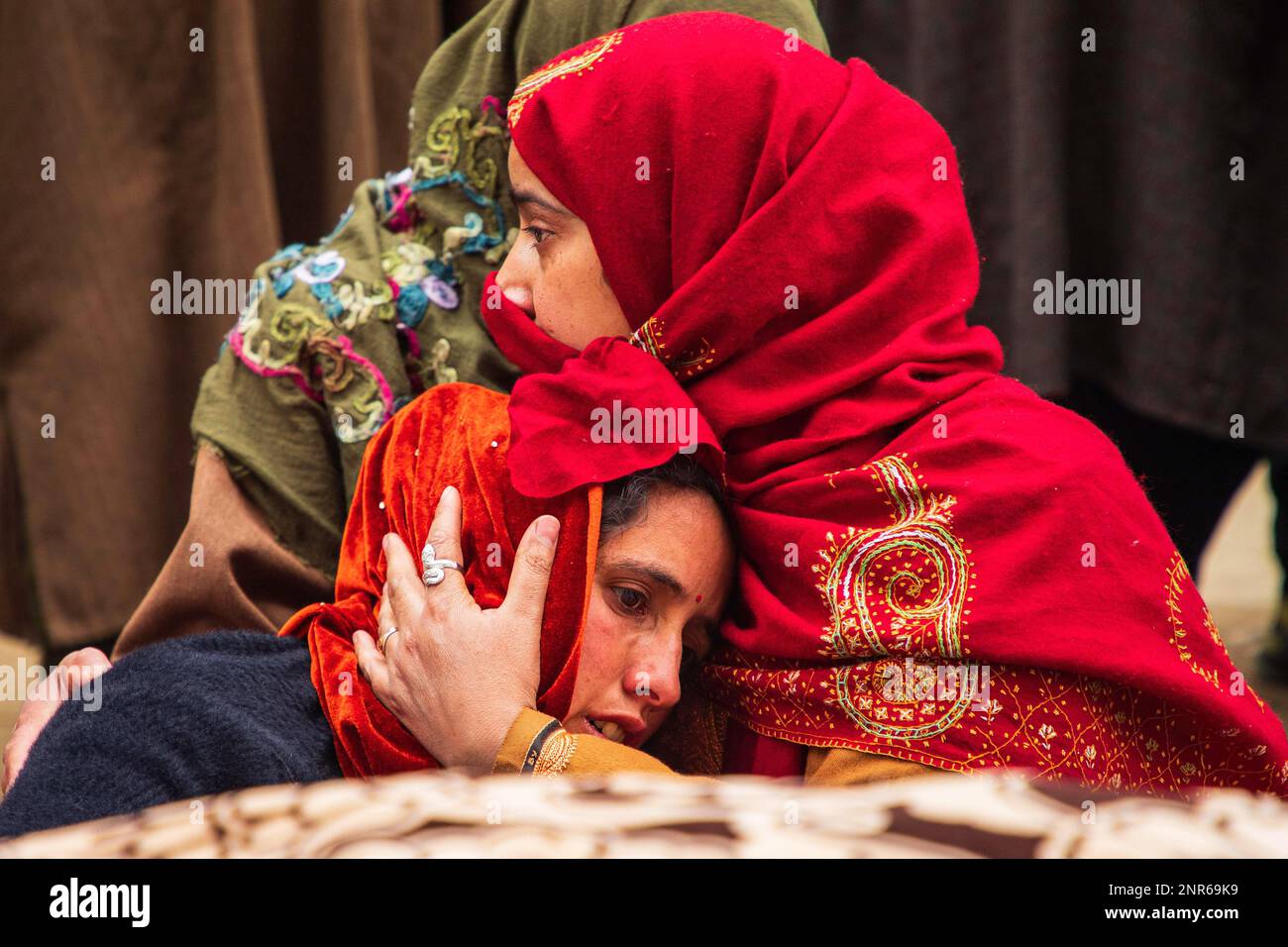 Srinagar, India. 25th Feb, 2023. A Kashmiri Muslim woman consoles a mourning wife of Sanjay Sharma a Kashmiri Hindu bank security guard who was shot dead by suspected militants in Pulwama South of Indian administered Kashmir. Police said suspected militants opened fire on Sanjay Sharma while he was on his way to a local market in Achan village Pulwama district. Credit: SOPA Images Limited/Alamy Live News Stock Photo