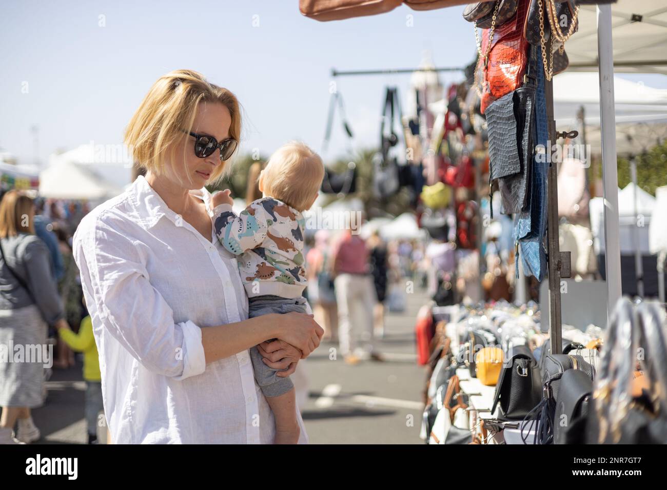 Mother hoding his infant baby boy child whilechecing items at sunday