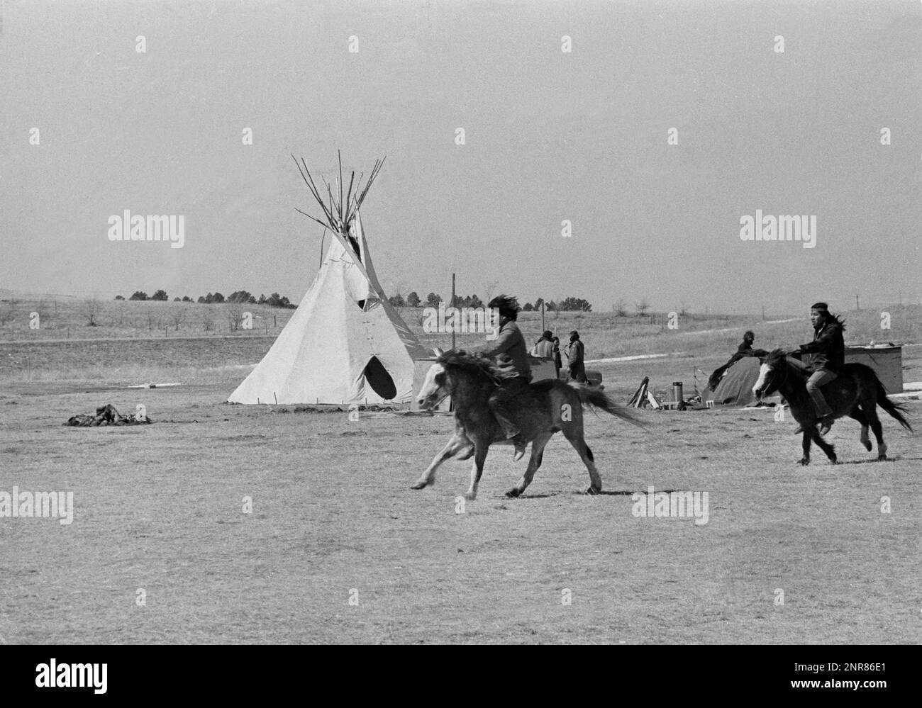 FILE Native American youths on horses ride past a tipi at Wounded
