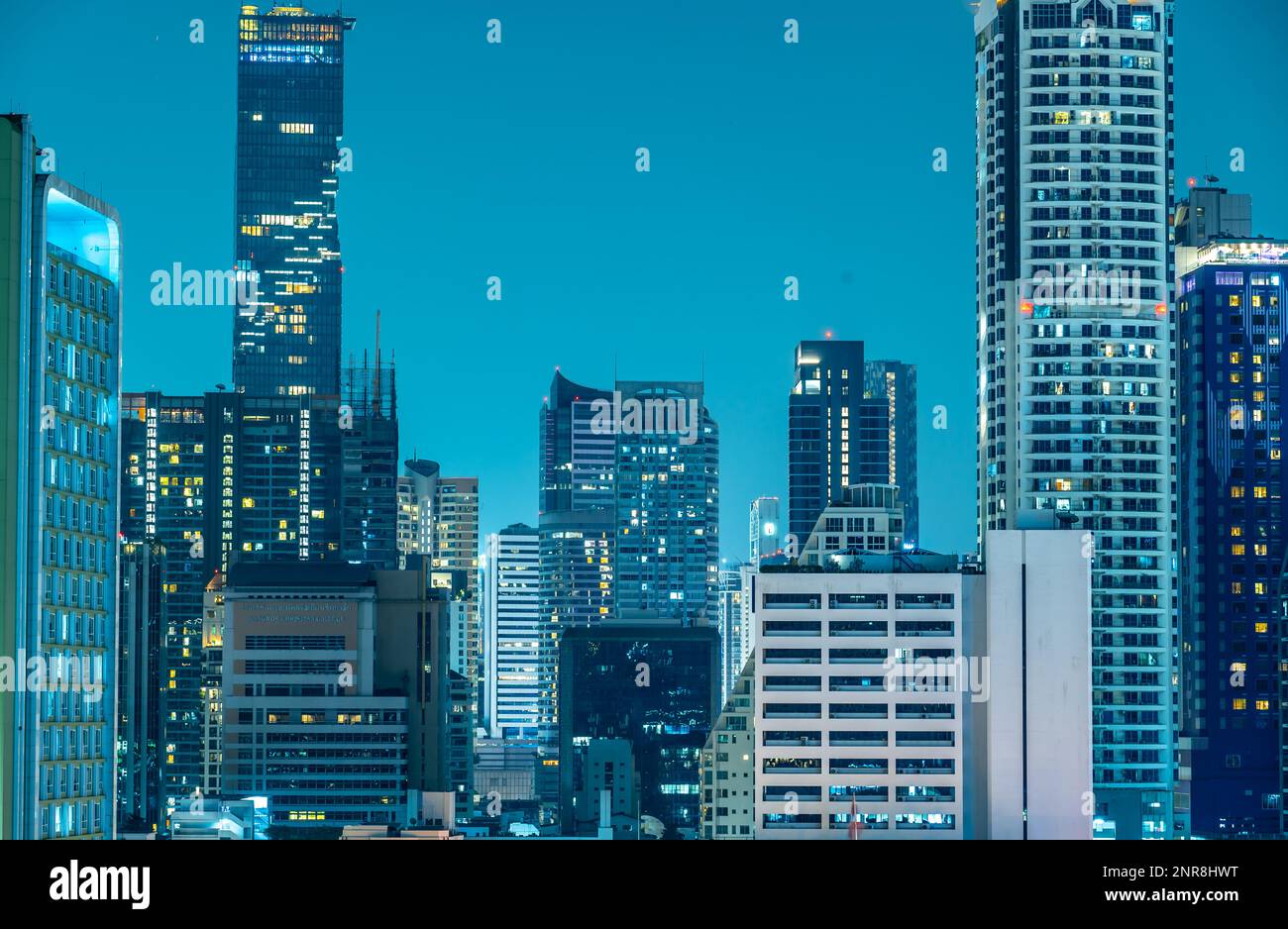 Modern skyscrapers illuminated at night reflecting on facade. Bangkok ...