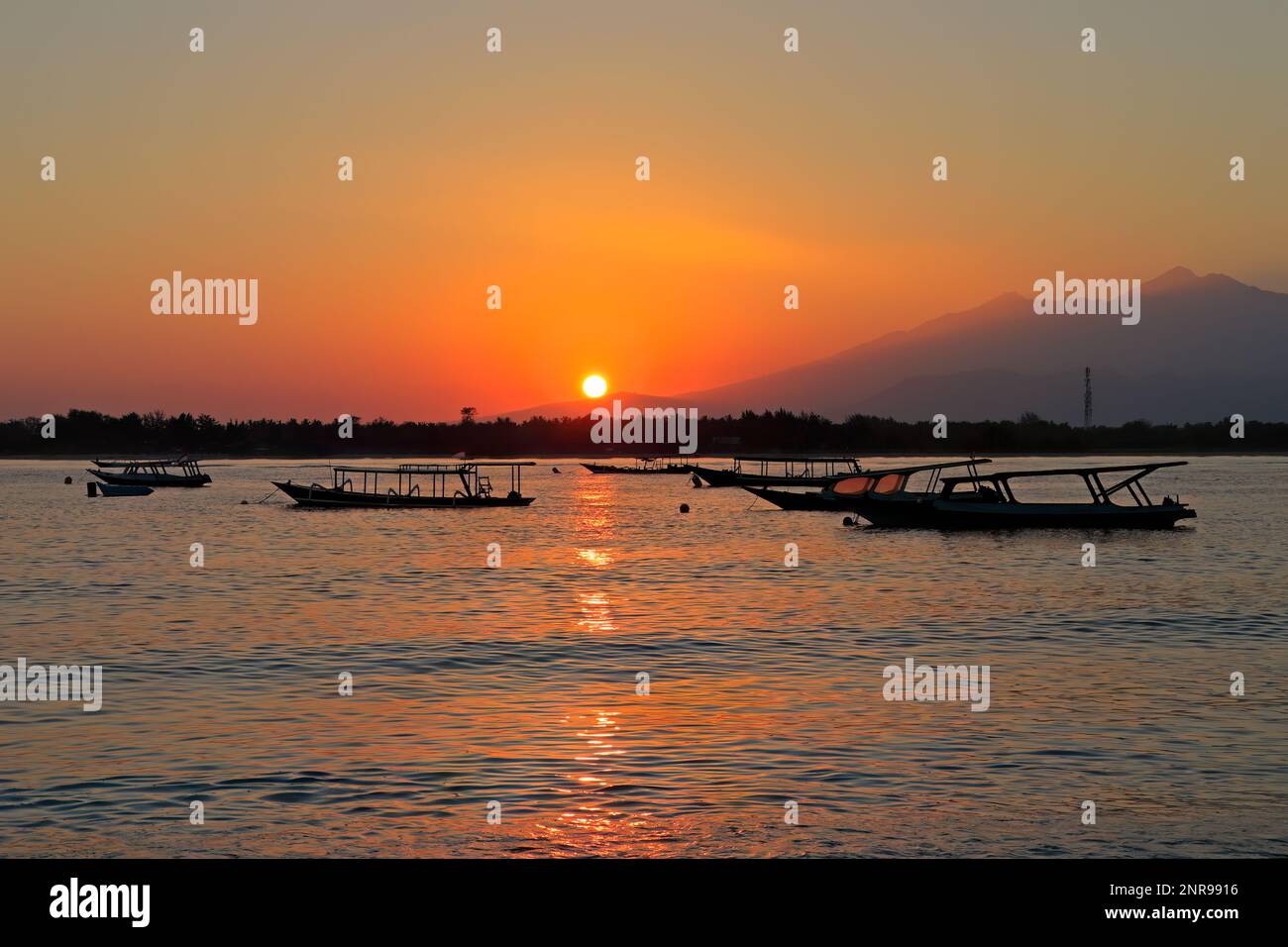 Scenic beach with boats silhouetted at sunset on a tropical island of Indonesia Stock Photo