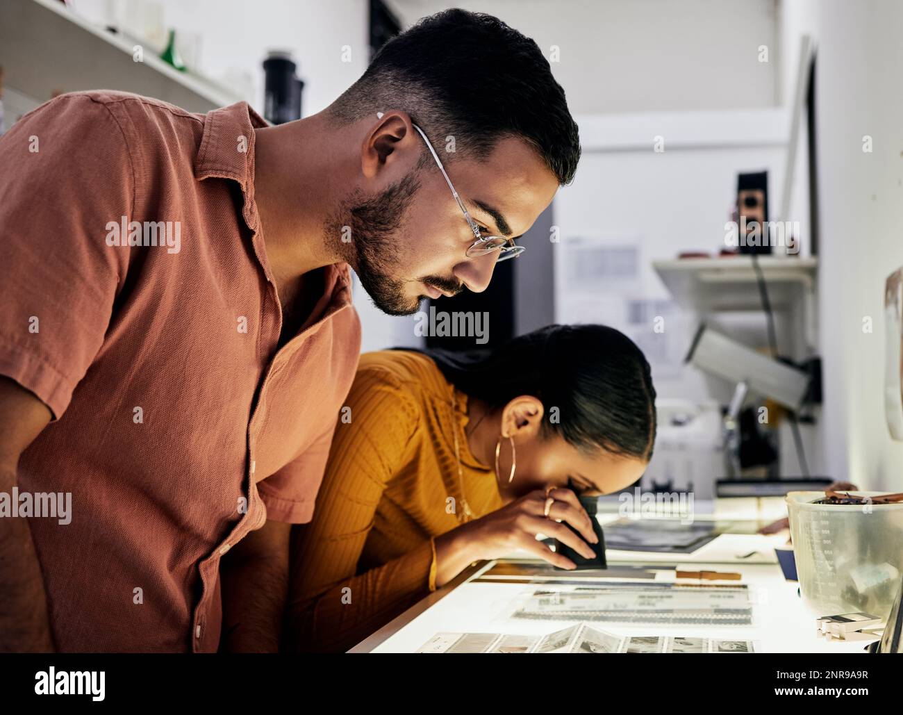 Photographer, editing and film negatives with looking, magnifying glass