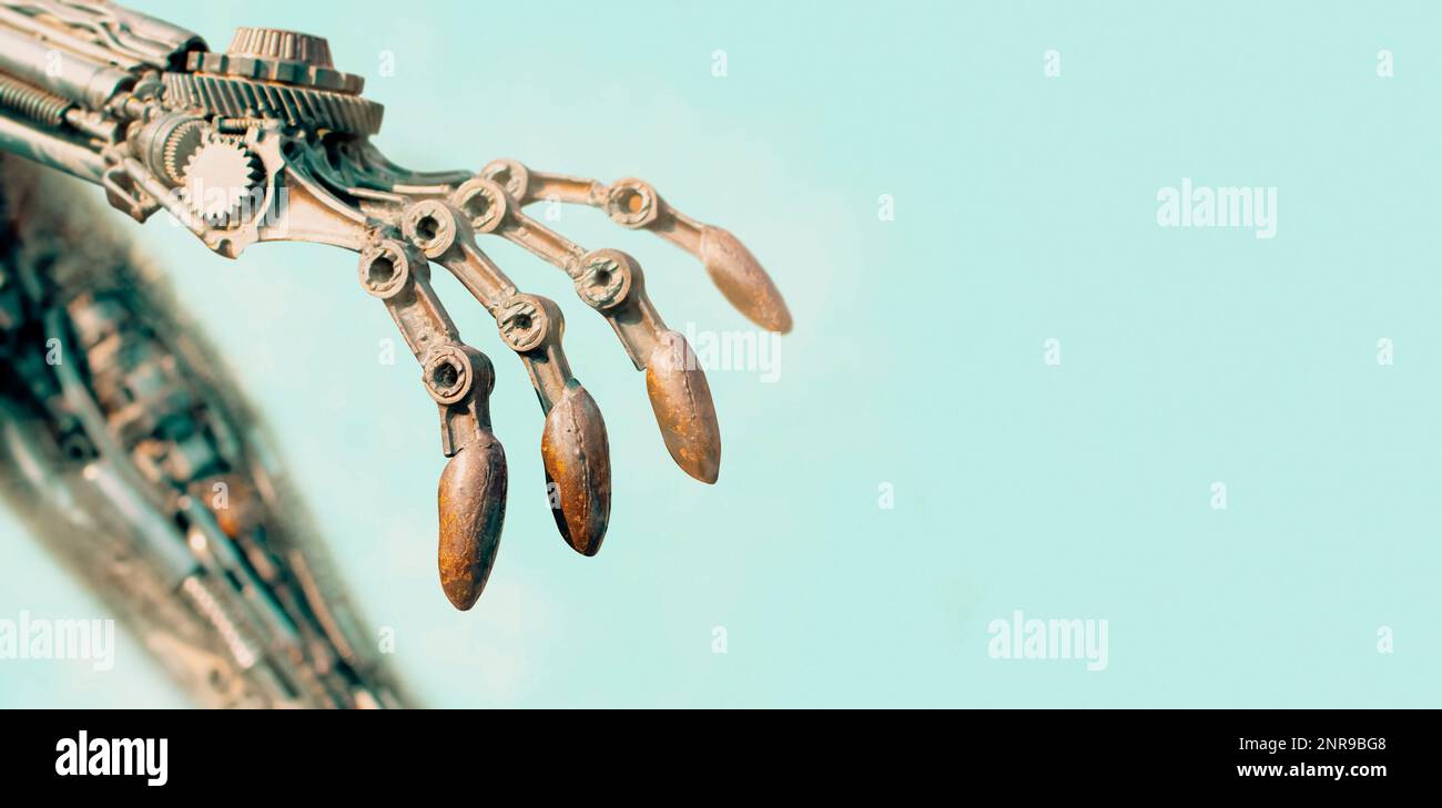 Closeup of an old rusty robot arm on a blue background, panoramic banner with copy space. Stock Photo