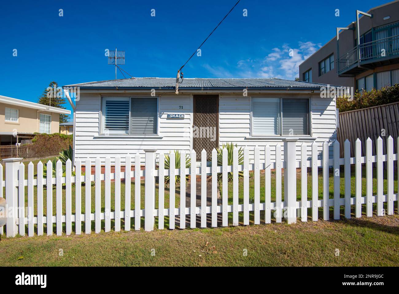 A white timber weatherboard cottage named The Shack with a white picket fence and corrugated fibro 'Super Six' roof at The Entrance in New South Wales Stock Photo
