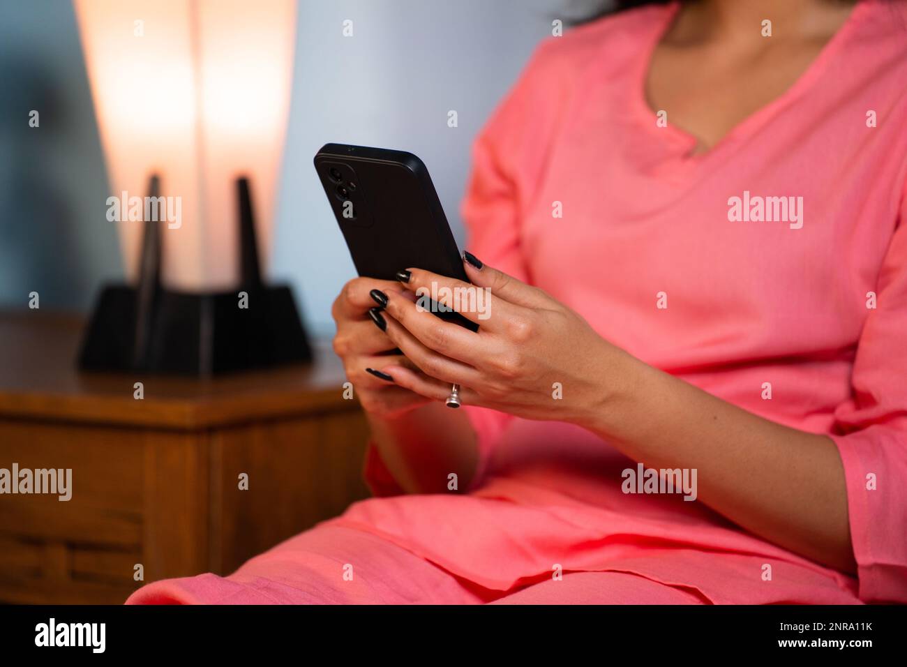 Close up shot of girl hand using mobile phone at home on bed during sleeping at night - concept of technology or internet addiction, chatting and Stock Photo