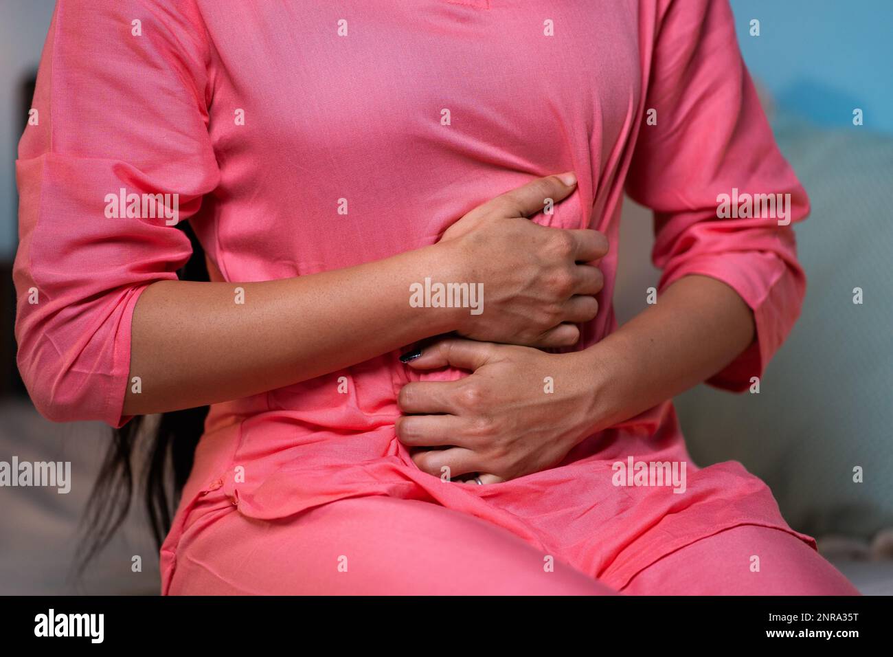 Close up shot of young girl suffering from stomach pain during night while sitting on sofa - concept of menstruation cycle, appendicitis and illens or Stock Photo