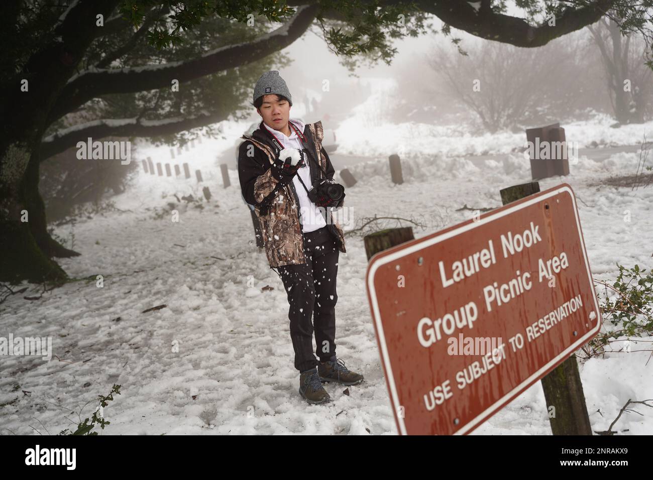 A man holds a snowball as he plays with snow. Heavy snow and rain have