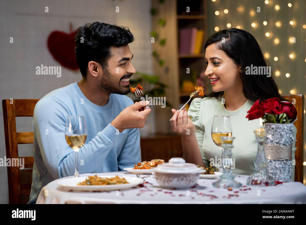 Happy young couple enjoying dinner by talking eachother during candle ...