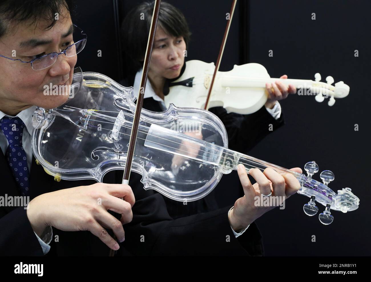 A photo shows a transparent plastic violin made by 3D printer (the back  violin is a non-transparent violin made two years ago) at Tokyo Big Sight  in Koto Ward, Tokyo on January