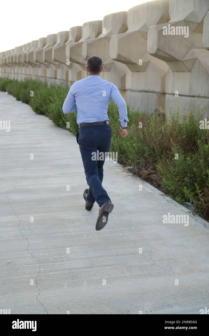 Rear view of man running away outdoors Stock Photo