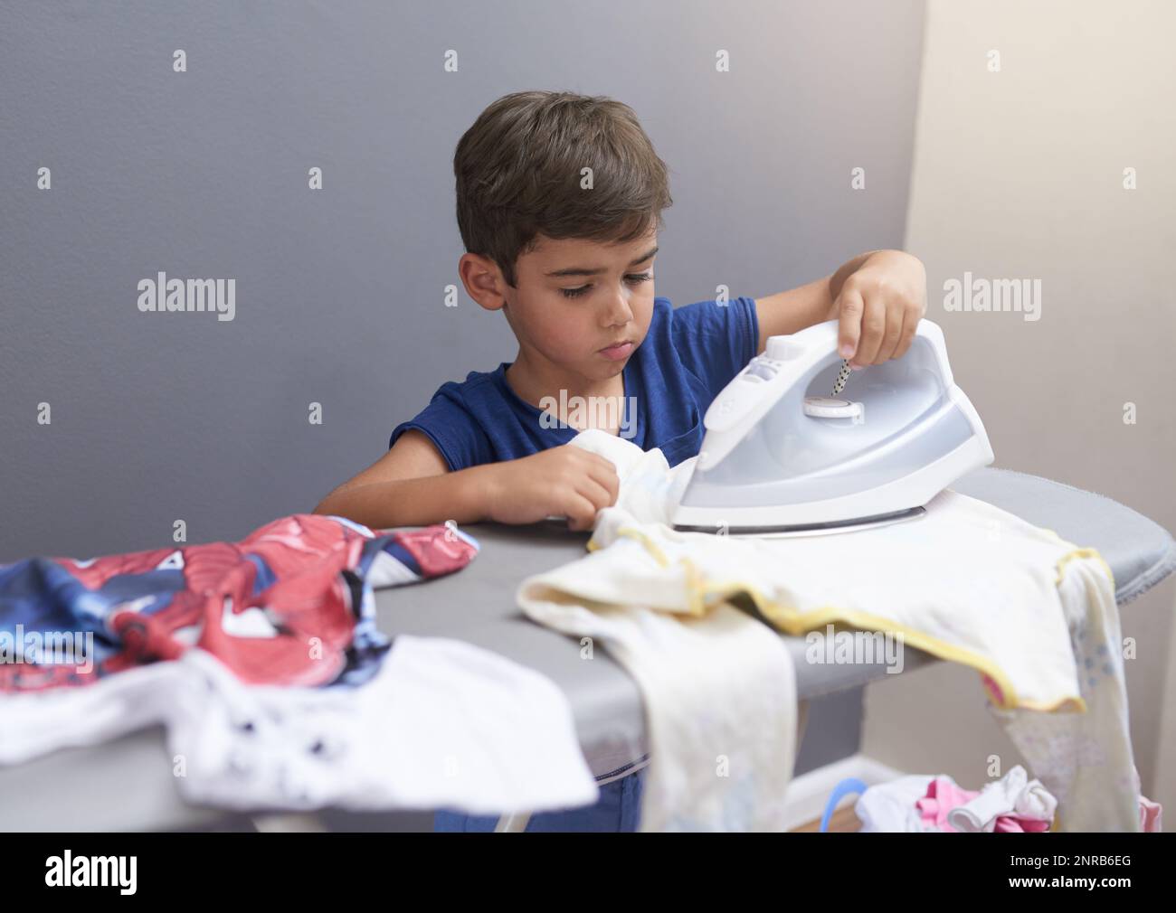 Learning the art of ironing. a little boy ironing clothes at home Stock