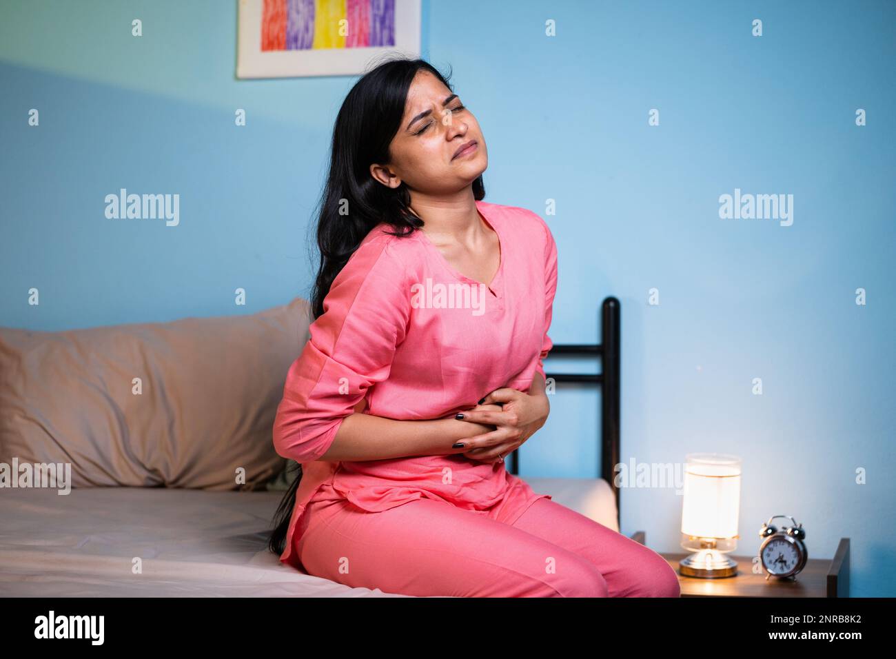 young girl suffering from stomach pain during night sleepon bed - concept of menstruation cycle, inflammation and illness or unhealthy Stock Photo