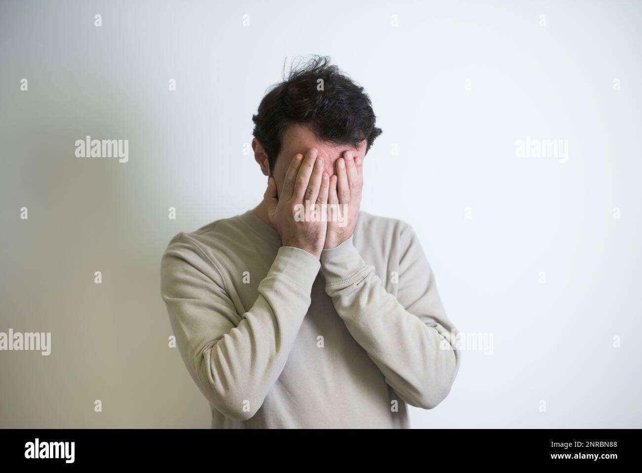 Man hiding face in hands crying Stock Photo