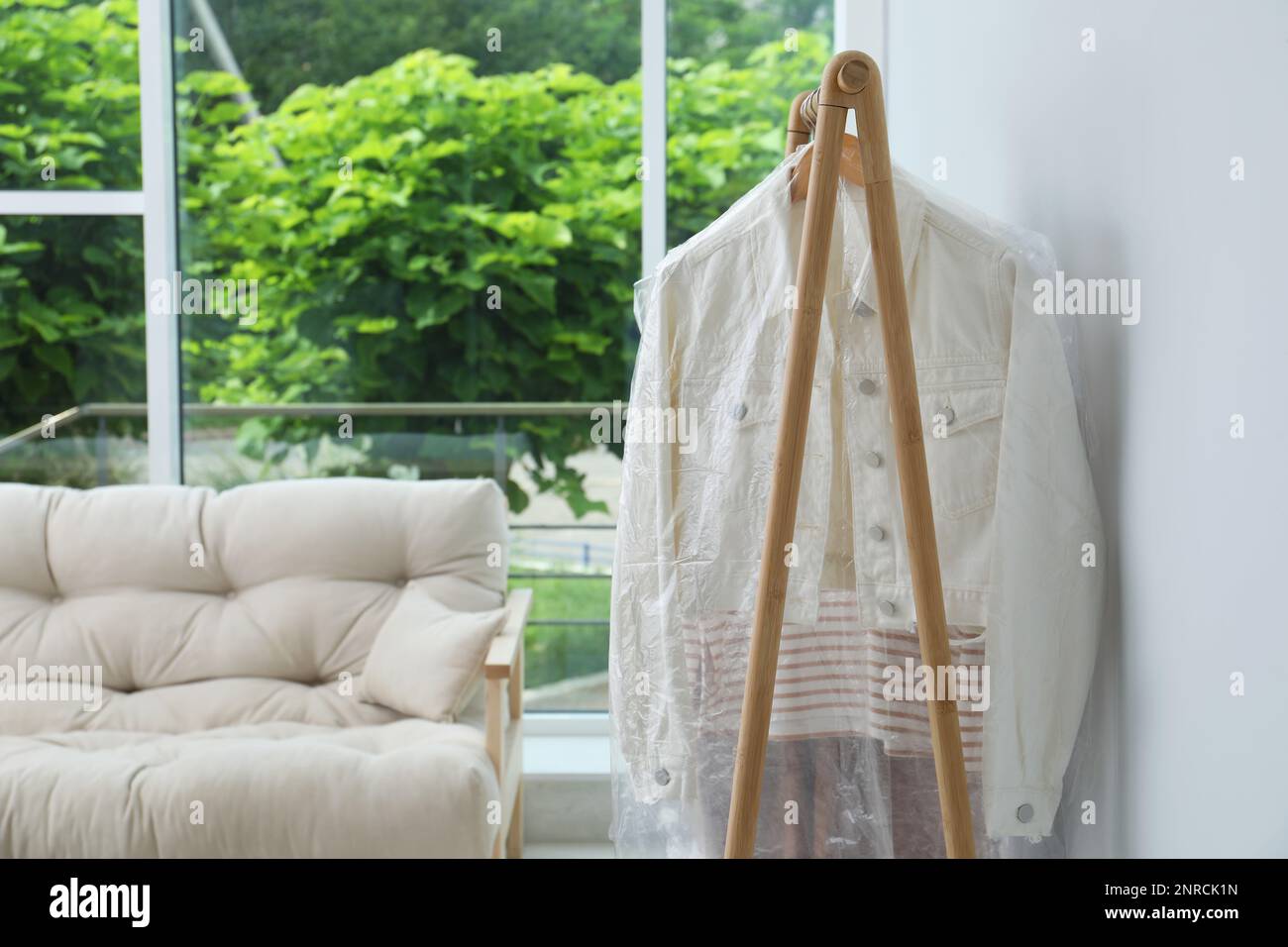 Rack with clothes in plastic bags indoors Stock Photo Alamy