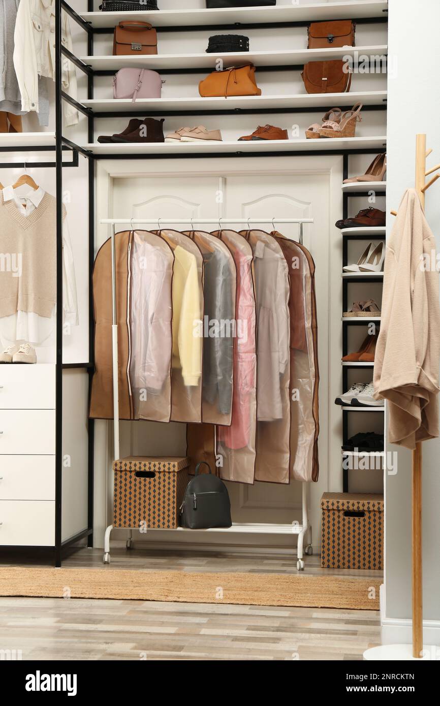 Garment bags with clothes on rack in dressing room Stock Photo - Alamy