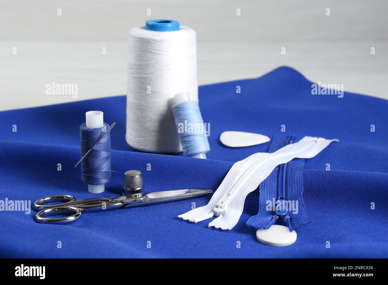 Composition with different sewing supplies on blue fabric Stock Photo