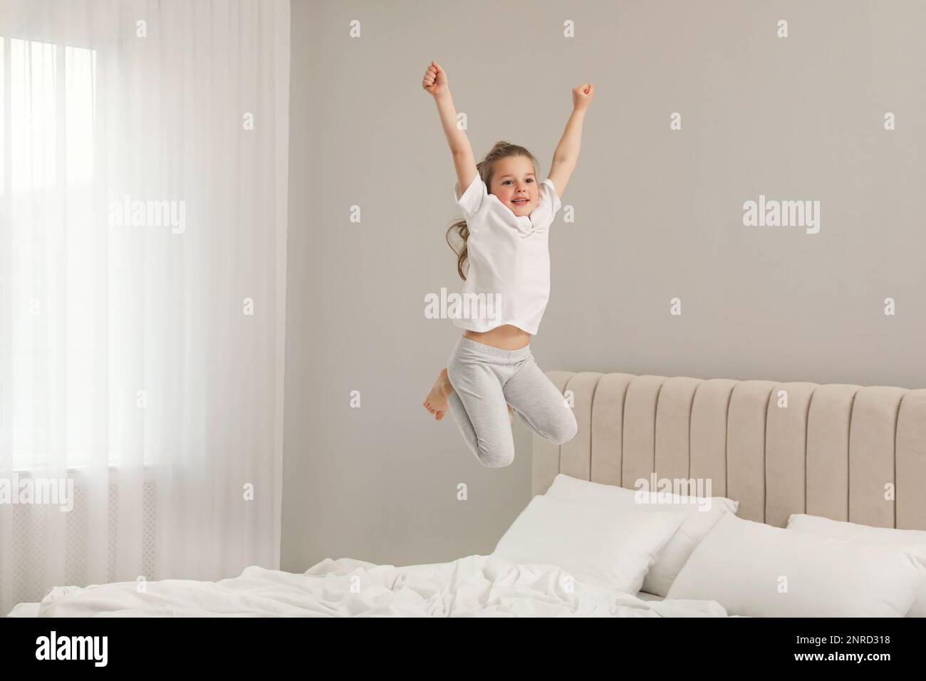 Cute little girl jumping on bed at home Stock Photo Alamy
