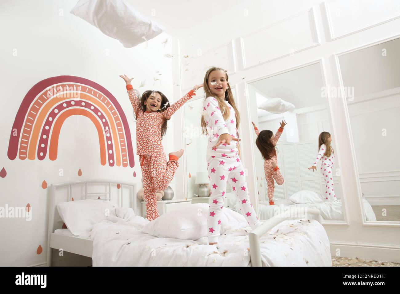 Cute little girls in pajamas playing on bed at home. Happy childhood ...