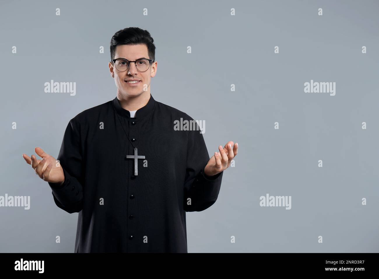Priest wearing cassock with clerical collar on grey background. Space for text Stock Photo