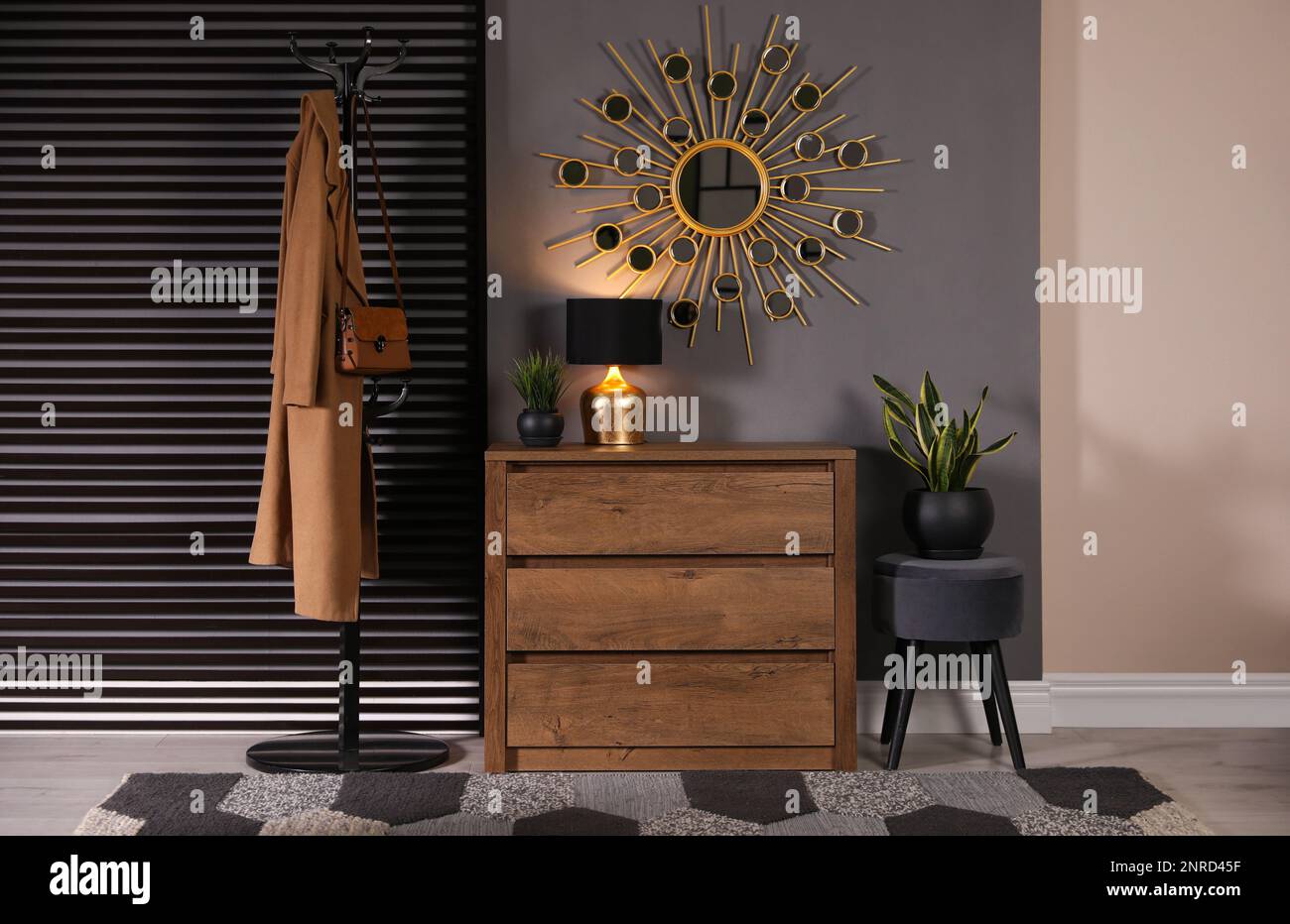 Wooden chest of drawers with decor, coat stand and mirror in hallway. Interior design Stock Photo