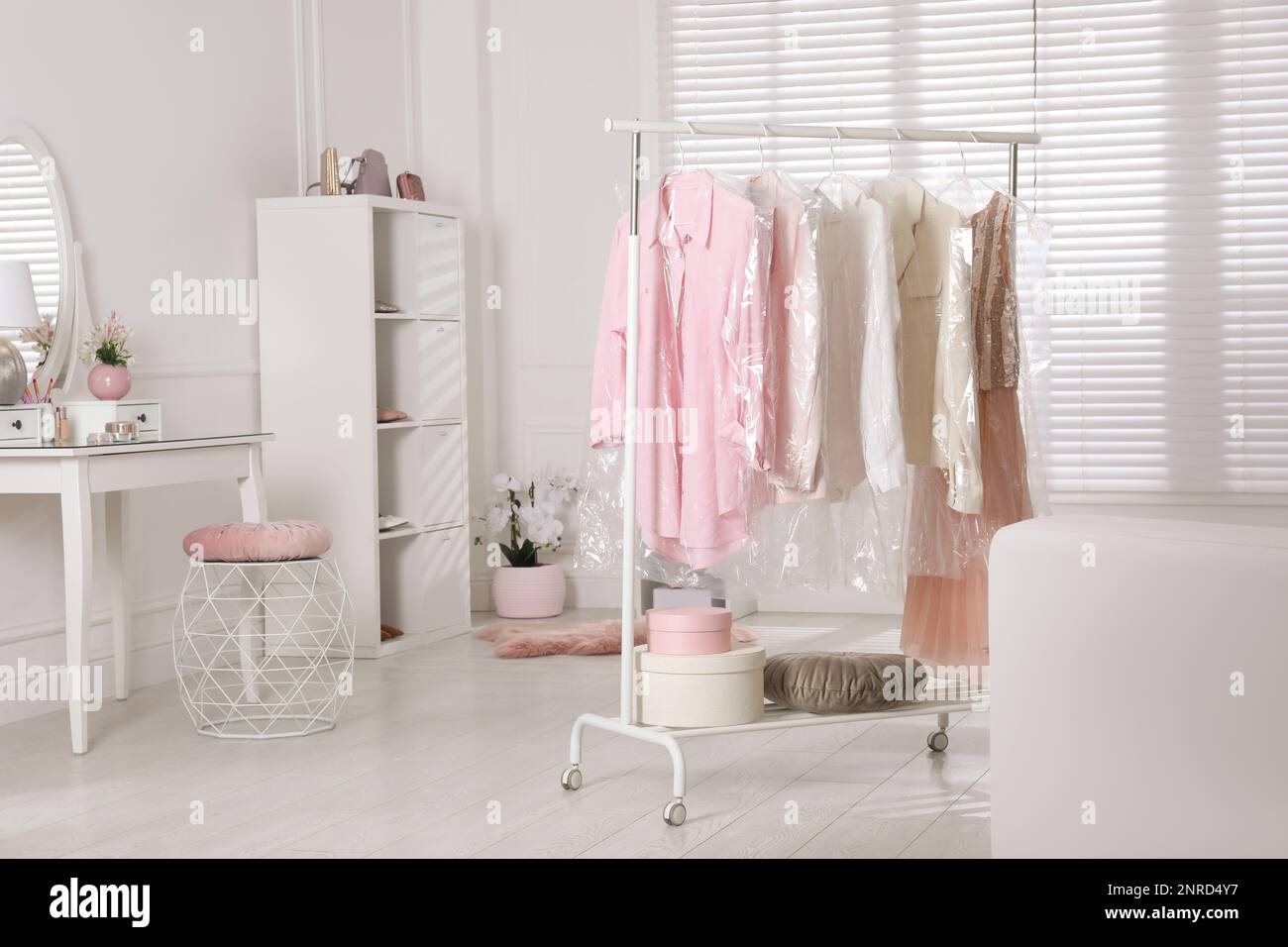 Rack with clothes in plastic bags indoors Stock Photo Alamy