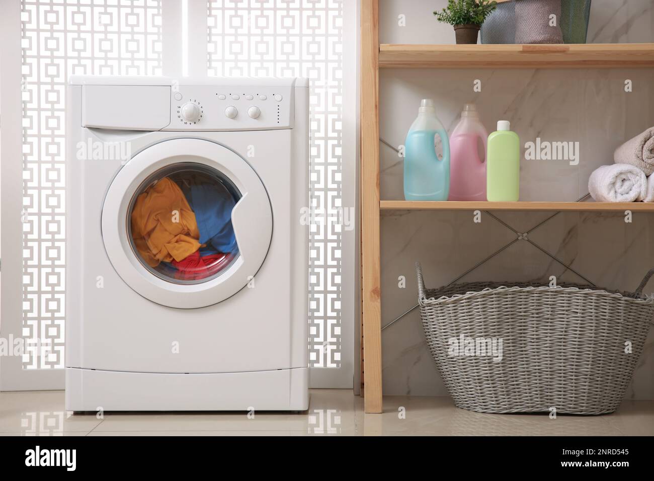 Modern washing machine with clothes in bathroom Stock Photo Alamy