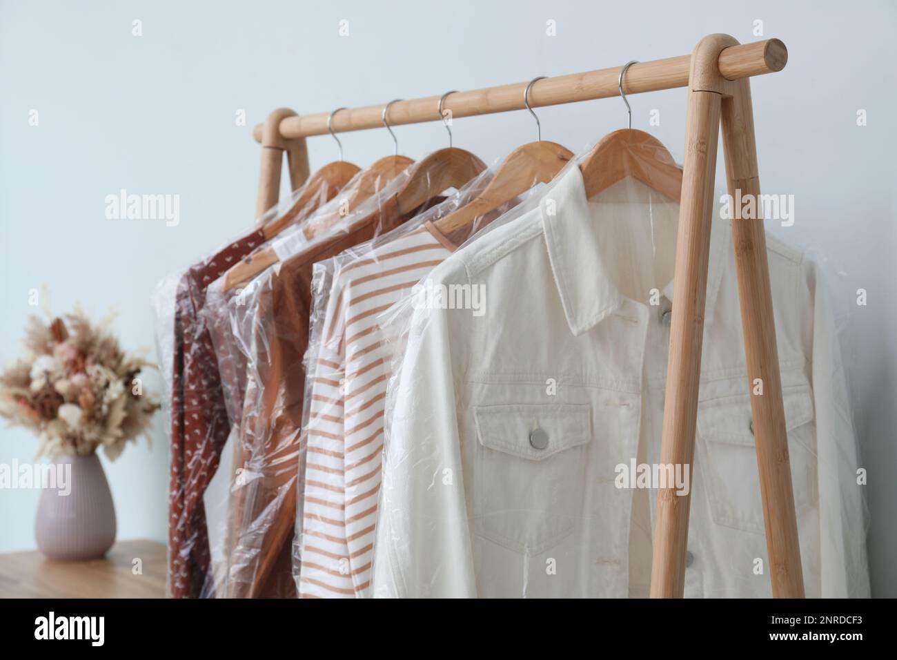 Rack with clothes in plastic bags indoors Stock Photo Alamy