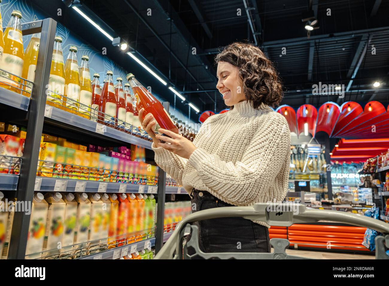 Shopper selects juice in grocery store with cart Stock Photo Alamy
