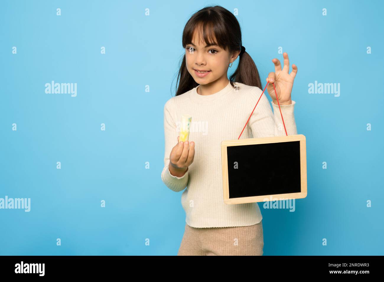 Portrait of girl with blackboard isolated on blue background Stock Photo