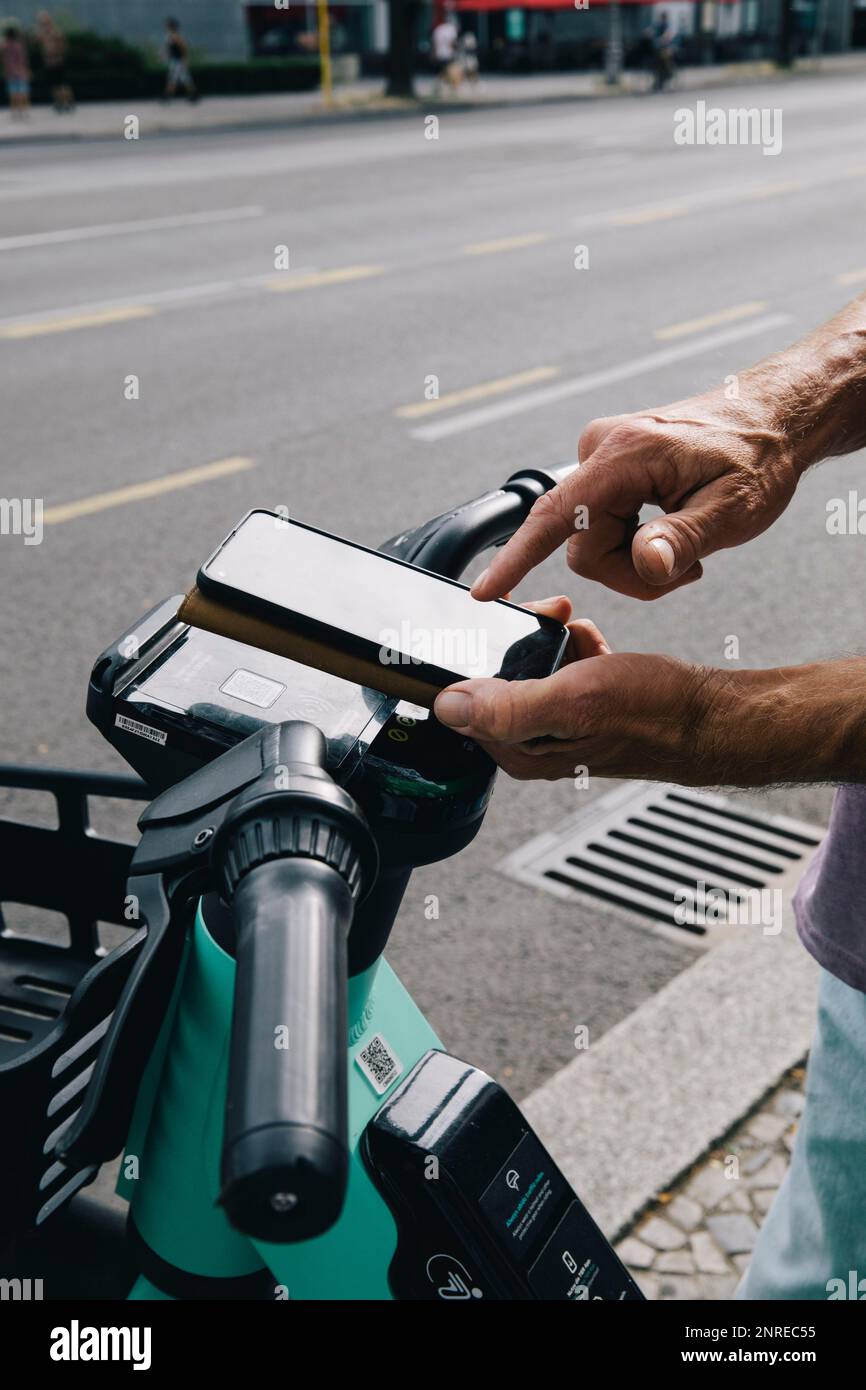 Close-up of hand unlocking electric push scooter using smart phone Stock Photo