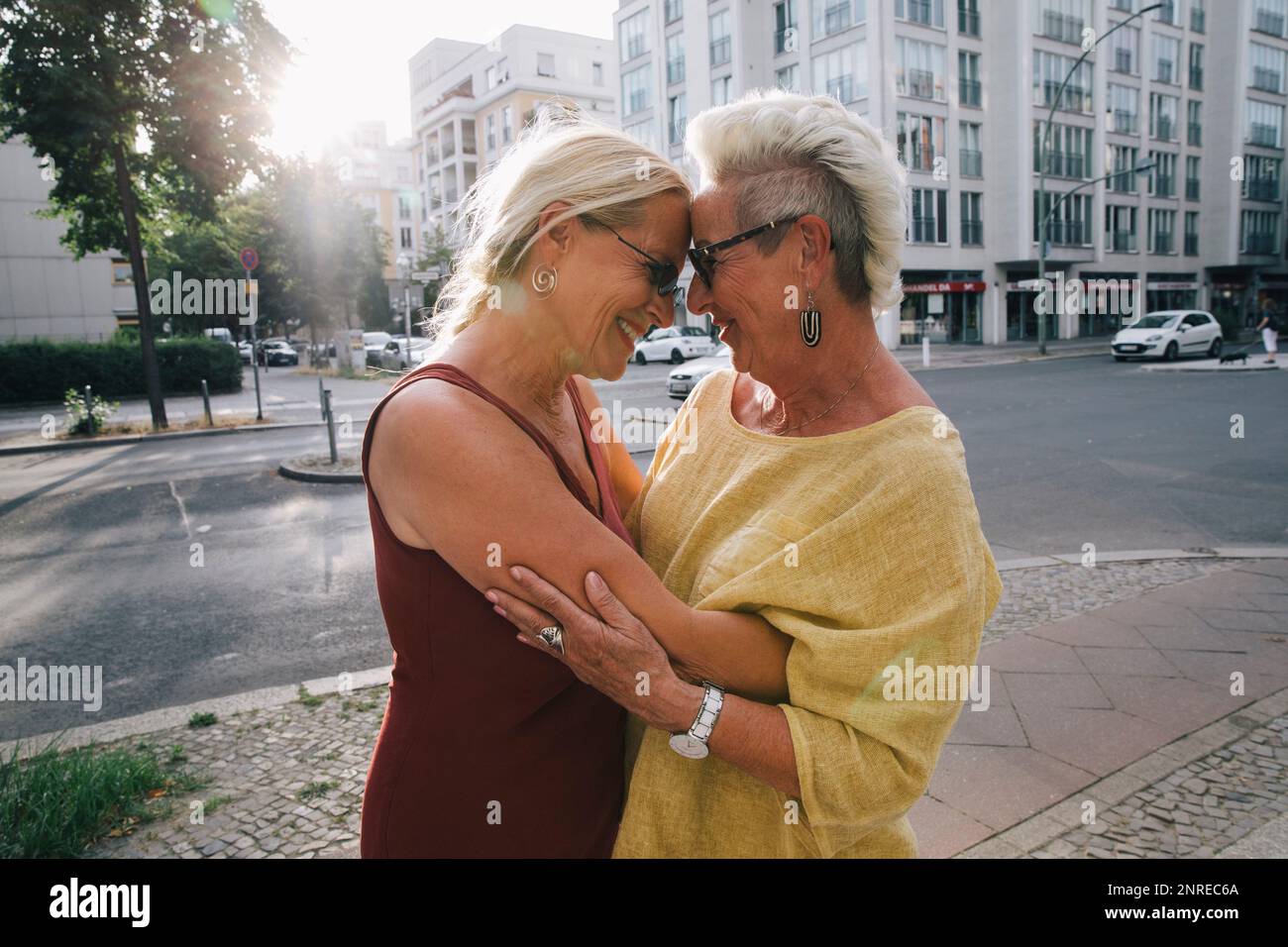 Two senior female woman embracing on city street Stock Photo