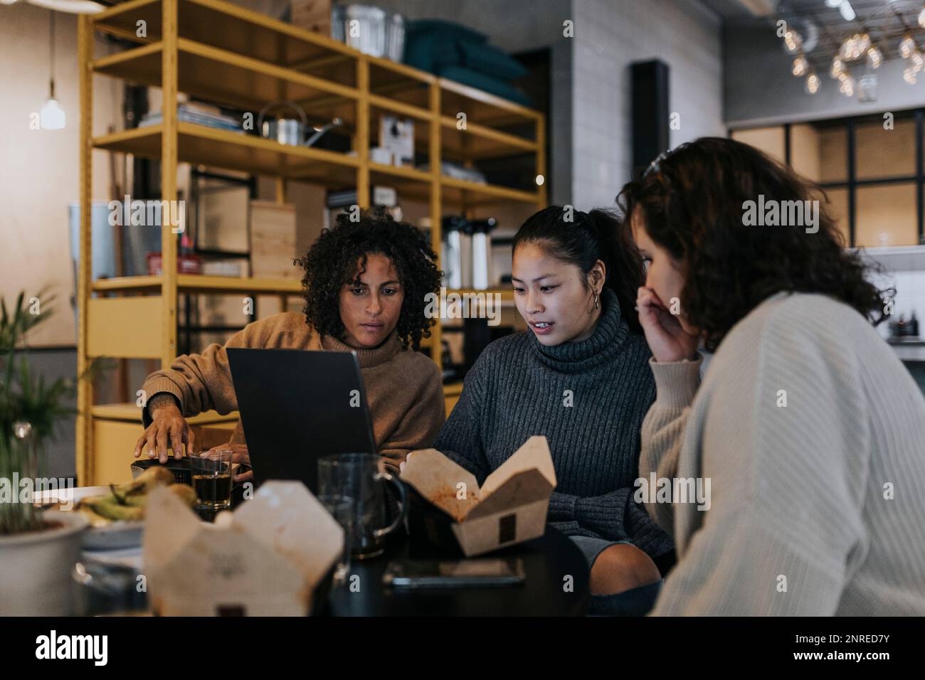 Multiracial female programmers discussing over laptop while working in startup company Stock Photo