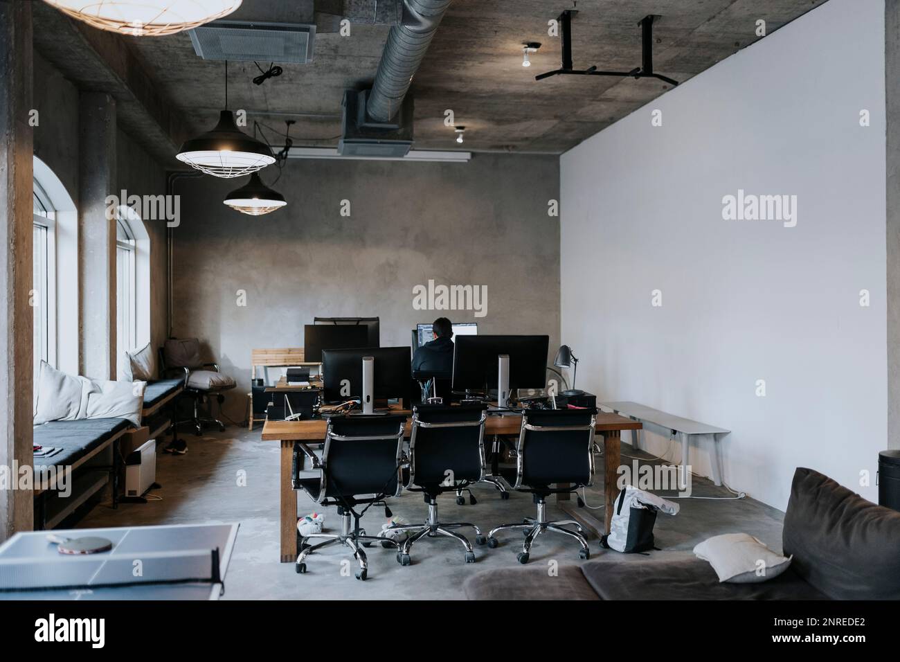 Rear view of male hacker working on computer in creative office Stock Photo